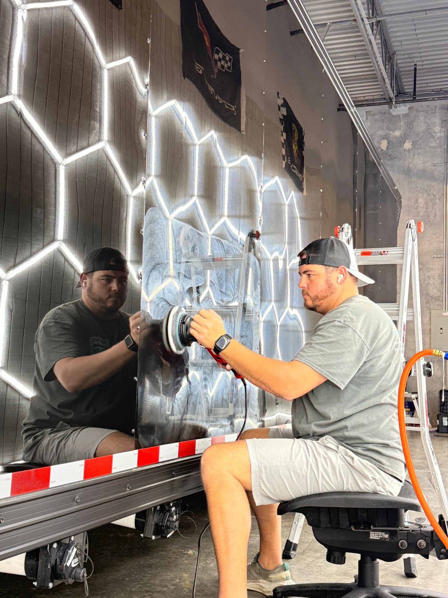 Holy City Auto Spa detailer polishing a reflective trailer panel under workshop lights